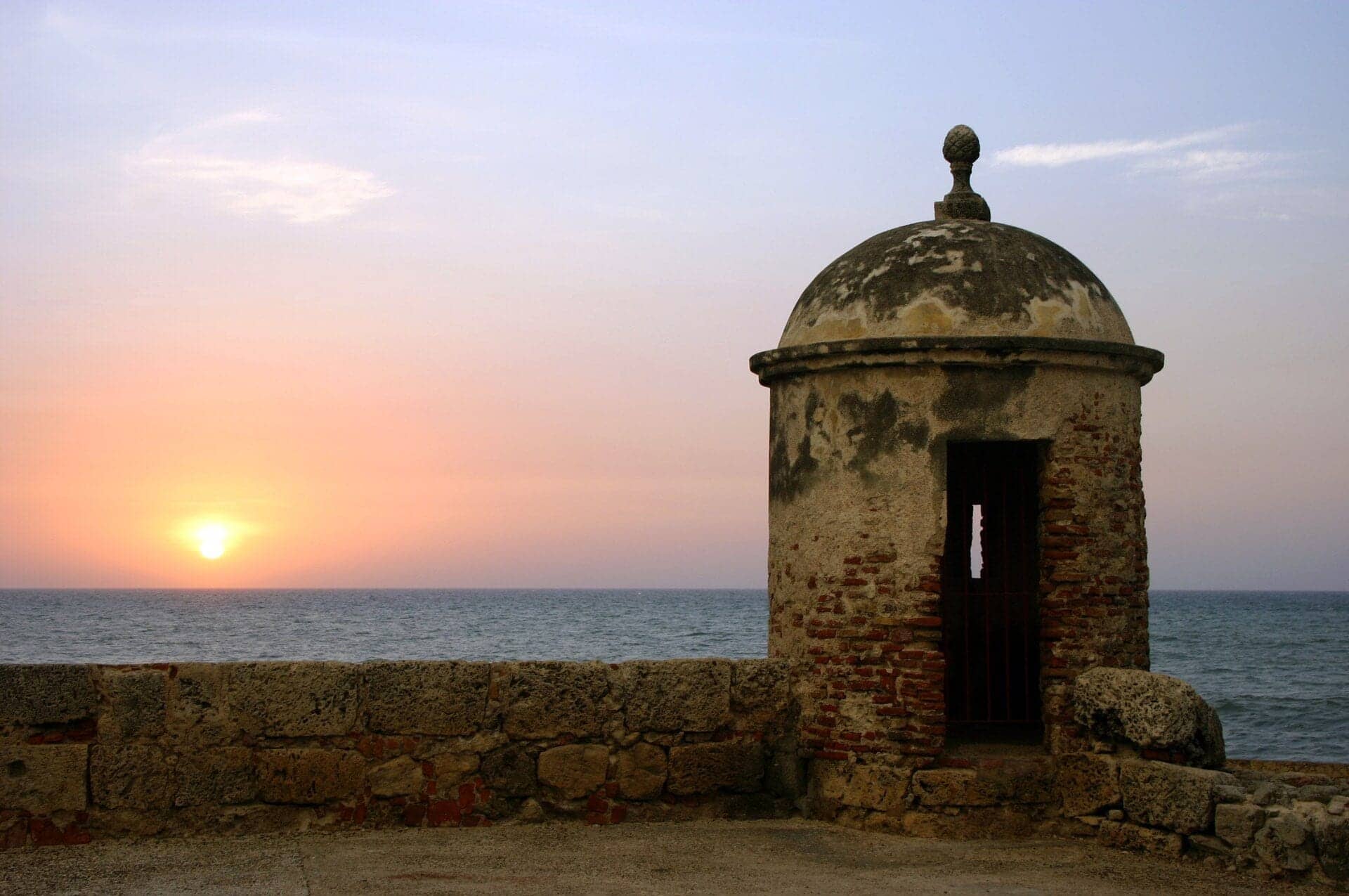 Puesta de sol sobre el mar junto a un torreón colonial de las murallas de Cartagena